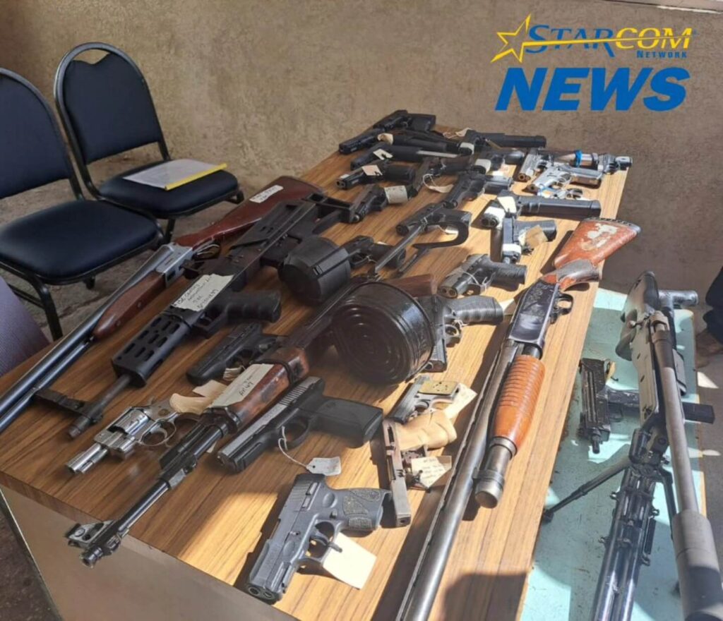 Numerous firearms of different types on a table.
